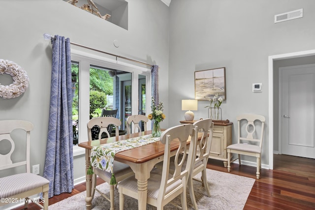 dining room with a towering ceiling, wood finished floors, and baseboards