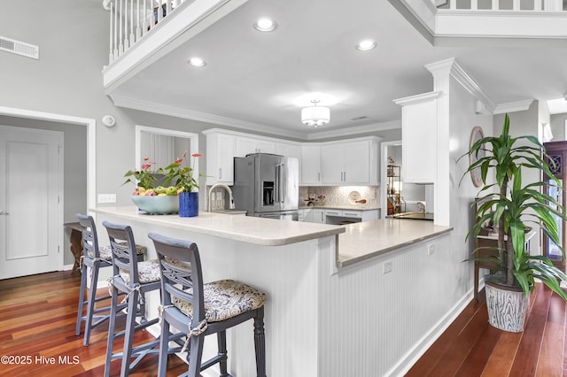 kitchen featuring stainless steel fridge with ice dispenser, light countertops, decorative backsplash, white cabinets, and crown molding