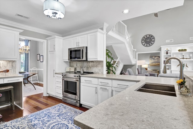 kitchen featuring stainless steel appliances, a chandelier, a sink, dark wood-type flooring, and white cabinetry