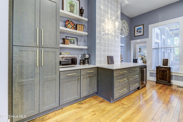 bar featuring stainless steel microwave, light wood finished floors, and wine cooler