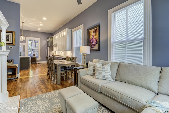 living area featuring light wood-type flooring, baseboards, and recessed lighting