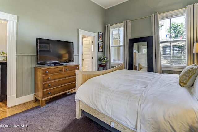 bedroom featuring multiple windows, wainscoting, and carpet floors