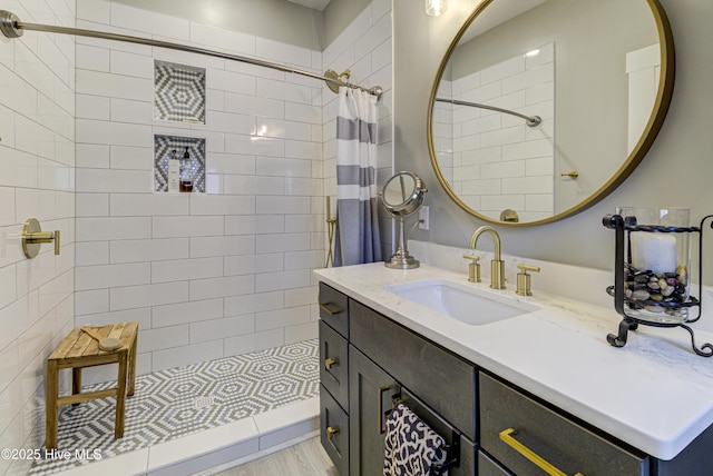 full bathroom featuring a tile shower and vanity