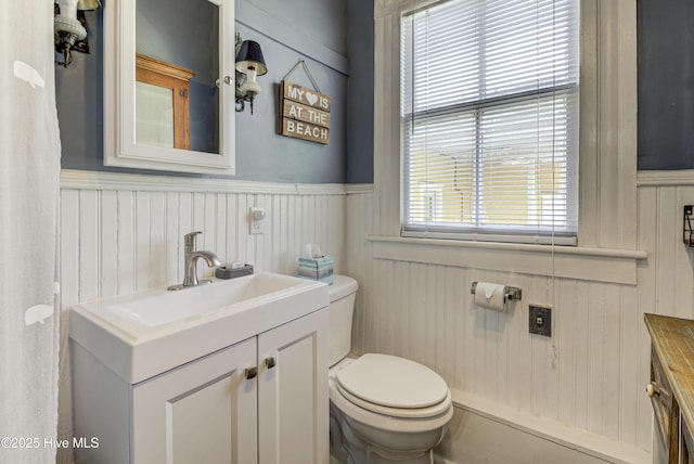 bathroom with vanity, toilet, wainscoting, and wooden walls