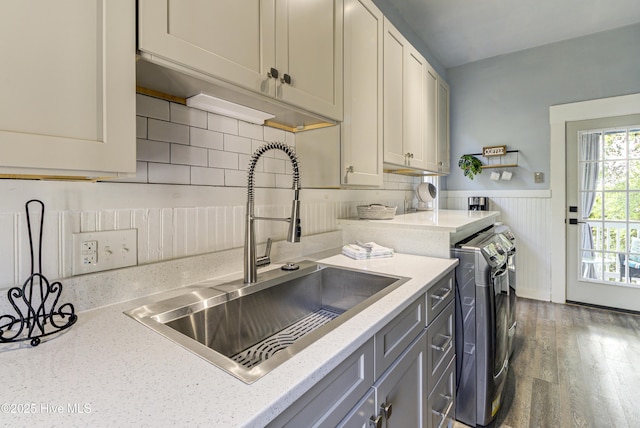 clothes washing area with washer and dryer, cabinet space, wainscoting, and wood finished floors