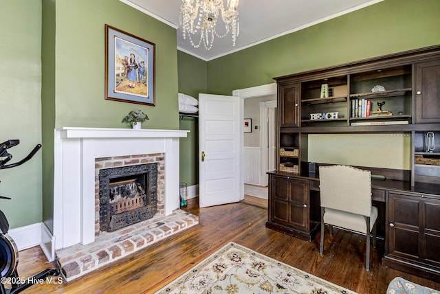 office featuring a chandelier, dark wood-type flooring, a fireplace, crown molding, and built in study area