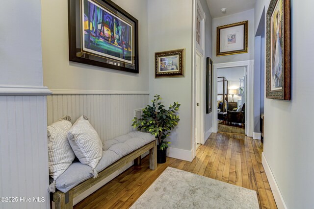 corridor with hardwood / wood-style flooring and wainscoting