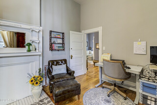 office area featuring light wood-type flooring and a high ceiling
