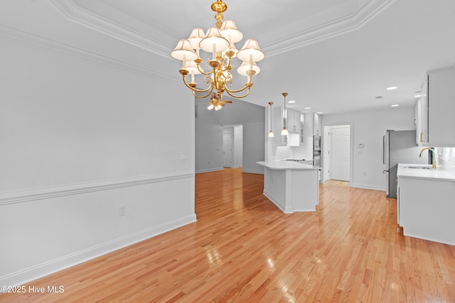 kitchen with a chandelier, light countertops, a sink, light wood-style floors, and crown molding