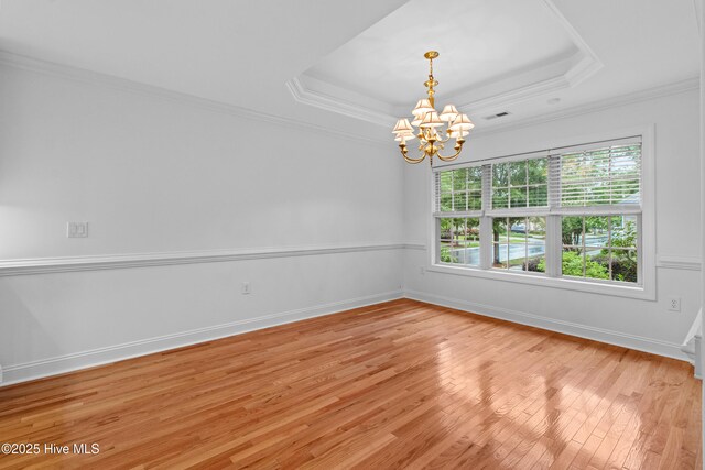 1103 Groppo Cv, Wilmington, NC 28412 - unfurnished room featuring a chandelier, a tray ceiling, light wood-type flooring, crown molding, and baseboards