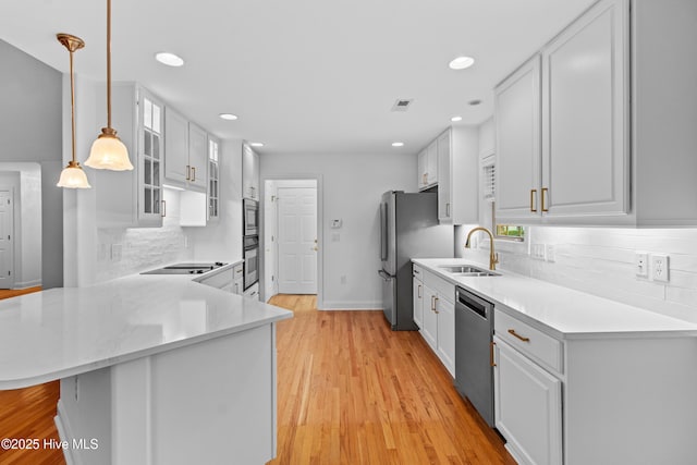 1103 Groppo Cv, Wilmington, NC 28412 - kitchen with appliances with stainless steel finishes, a sink, tasteful backsplash, glass insert cabinets, and a peninsula