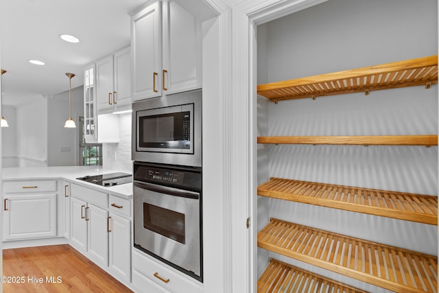 kitchen featuring stainless steel appliances, white cabinetry, open shelves, light countertops, and decorative backsplash