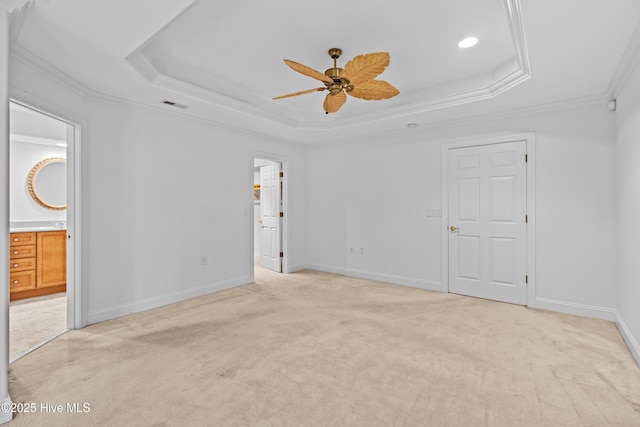 unfurnished bedroom featuring a raised ceiling, light colored carpet, crown molding, and baseboards