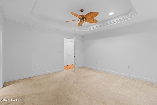 unfurnished room with a raised ceiling, carpet floors, crown molding, a ceiling fan, and baseboards