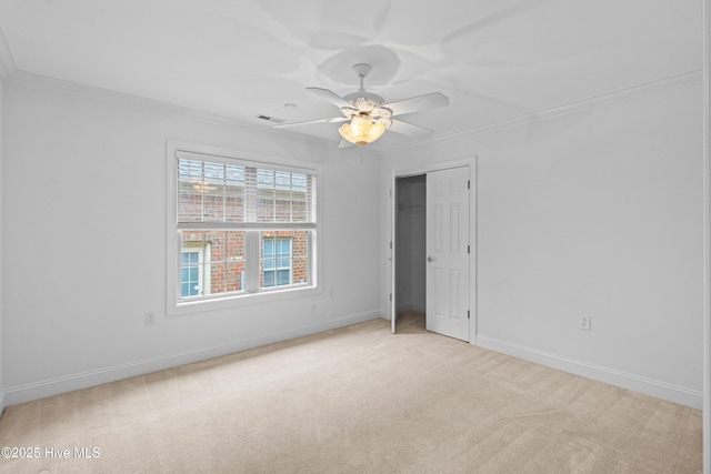 unfurnished bedroom featuring ornamental molding, light colored carpet, baseboards, ceiling fan, and a closet