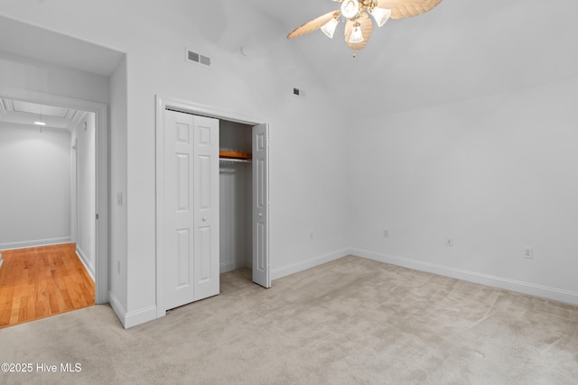 unfurnished bedroom with attic access, carpet flooring, a closet, baseboards, and a ceiling fan