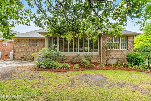 view of front of property with crawl space, brick siding, a sunroom, and roof with shingles