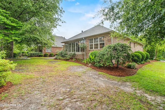 rear view of property featuring brick siding and a yard