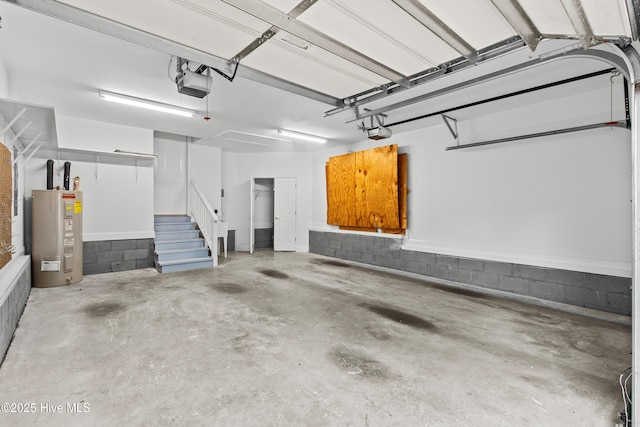 garage with water heater, a garage door opener, and concrete block wall