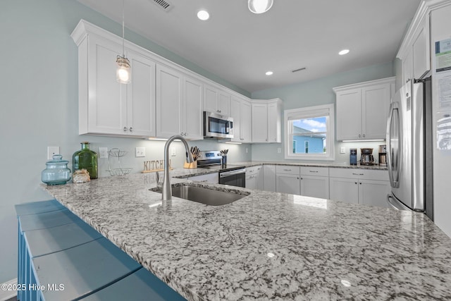 130 N Permuda Wynd Dr, North Topsail Beach, NC 28460 - kitchen with appliances with stainless steel finishes, a sink, light stone counters, white cabinetry, and pendant lighting