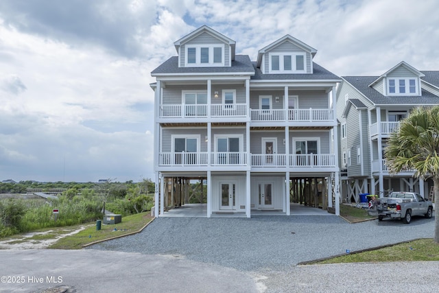 128 Sea Oaks Ct, North Topsail Beach, NC 28460 - coastal inspired home featuring a carport, gravel driveway, french doors, a balcony, and roof with shingles