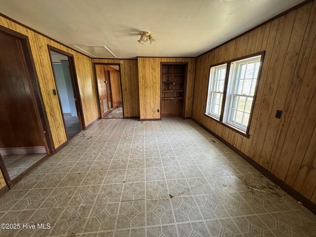 unfurnished bedroom featuring wooden walls, baseboards, and tile patterned floors