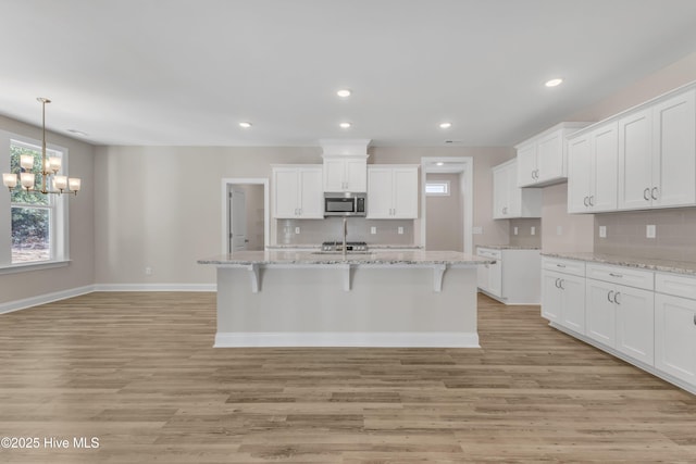 kitchen featuring stainless steel microwave, tasteful backsplash, light wood finished floors, and recessed lighting
