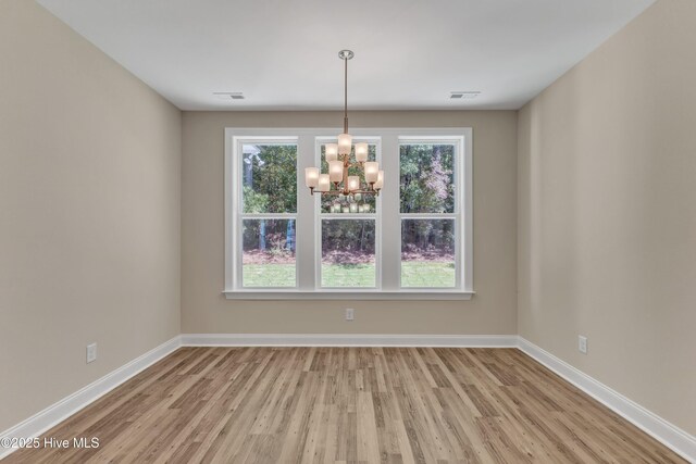 unfurnished dining area with a chandelier, wood finished floors, and baseboards