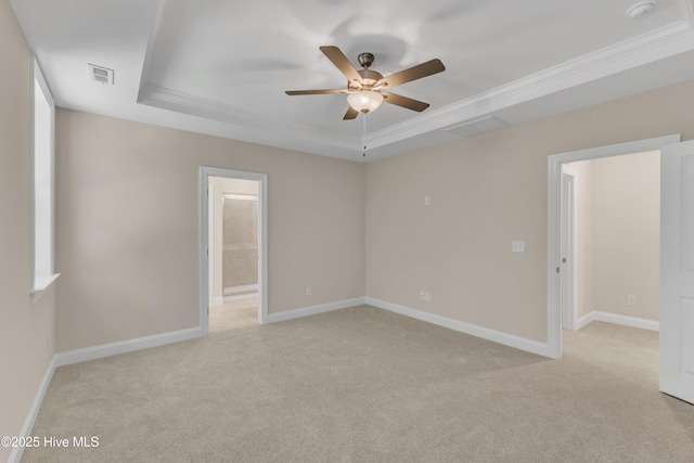 spare room featuring a tray ceiling, ceiling fan, light colored carpet, crown molding, and baseboards