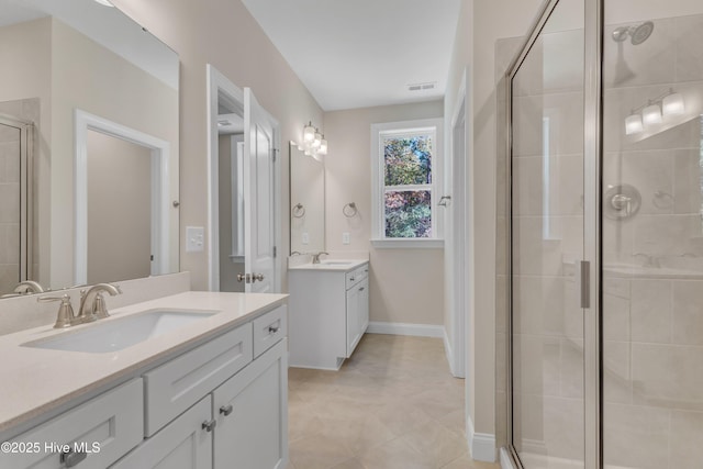 full bathroom with a stall shower, two vanities, tile patterned flooring, and baseboards