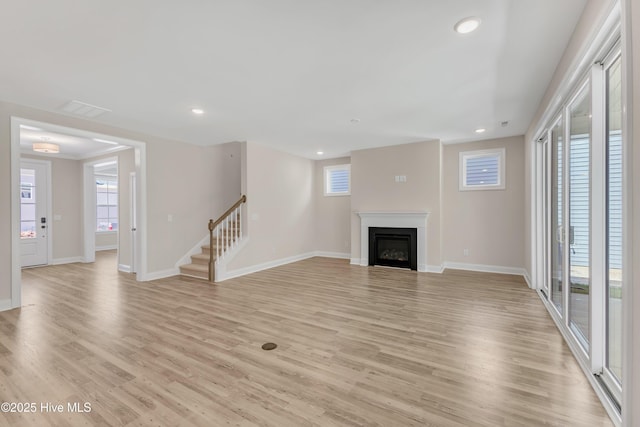 unfurnished living room featuring light wood finished floors, baseboards, stairs, and recessed lighting