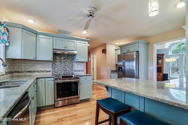 265 Creek View Dr, Sunset Beach, NC 28468 - kitchen featuring stainless steel appliances, a sink, light wood-style flooring, backsplash, and under cabinet range hood