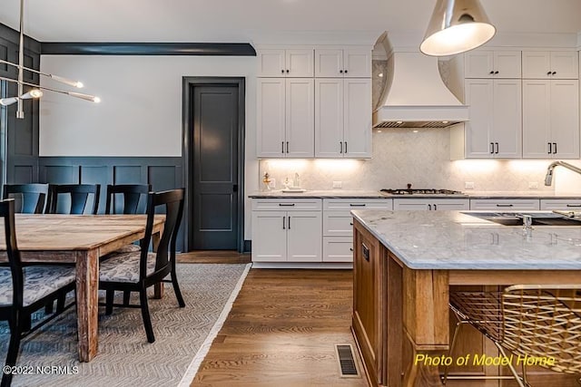 779 Breezewood Dr SE, Bolivia, NC 28422 - kitchen featuring premium range hood, a sink, stainless steel gas cooktop, dark wood-type flooring, and white cabinetry