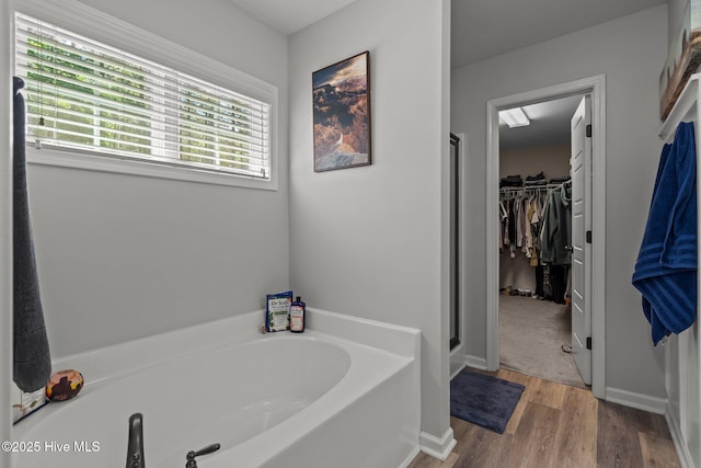 140 Timberwood Dr, Cameron, NC 28326 - bathroom featuring a bath, wood finished floors, a spacious closet, and a stall shower