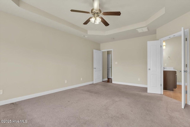 132 Turquoise Dr, Jacksonville, NC 28546 - unfurnished bedroom with a tray ceiling, carpet, baseboards, ensuite bathroom, and a ceiling fan