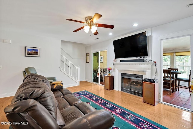 living room featuring a ceiling fan, stairs, wood finished floors, and recessed lighting