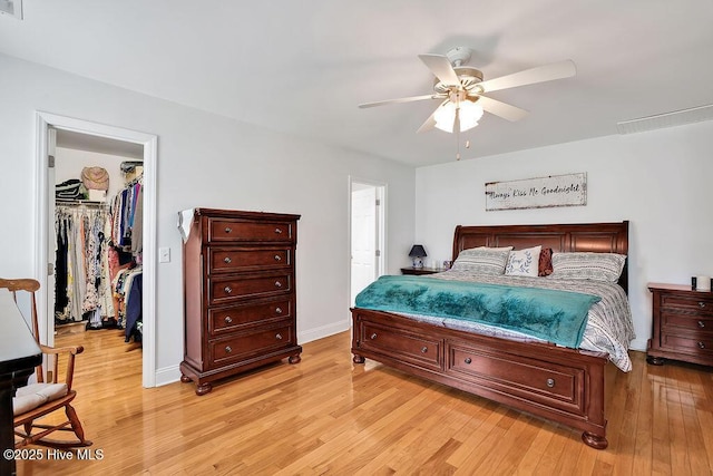 bedroom with a walk in closet, light wood-type flooring, a closet, and baseboards