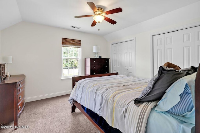 bedroom with two closets, baseboards, carpet flooring, vaulted ceiling, and a ceiling fan