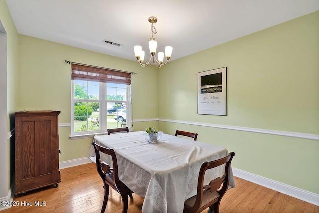 dining space featuring a chandelier, light wood-type flooring, and baseboards