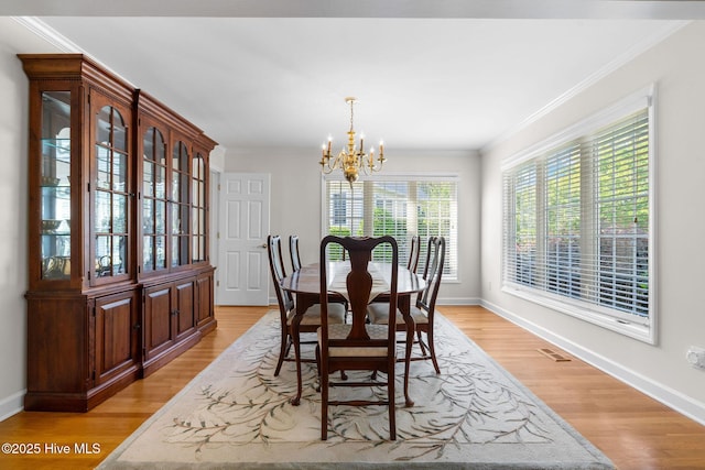 dining space featuring a chandelier, ornamental molding, light wood-type flooring, and baseboards