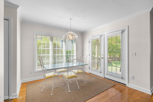 dining area featuring wood finished floors, crown molding, baseboards, and a chandelier