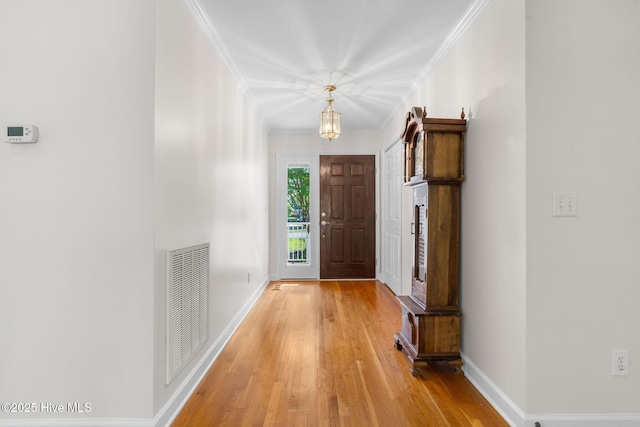 doorway featuring light wood-style floors, baseboards, and crown molding