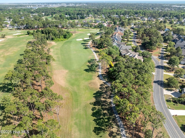 aerial view of property's location featuring a local golf course, nearby suburban area, and a tree filled landscape