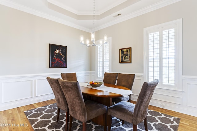 2016 Ashbrook Ct, Leland, NC 28451 - dining area featuring a chandelier, light wood finished floors, a wainscoted wall, a decorative wall, and a tray ceiling