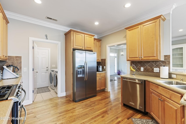 2016 Ashbrook Ct, Leland, NC 28451 - kitchen featuring appliances with stainless steel finishes, washing machine and clothes dryer, a sink, ornamental molding, and decorative backsplash