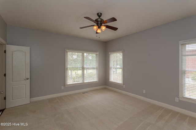 empty room featuring baseboards, light colored carpet, and a ceiling fan