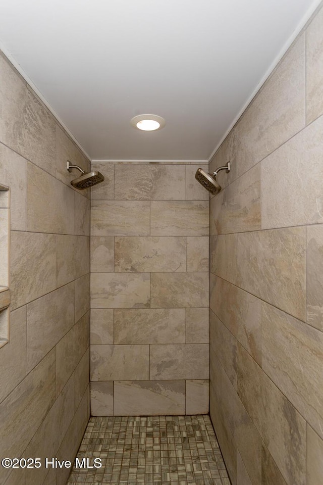 bathroom with a tile shower and ornamental molding