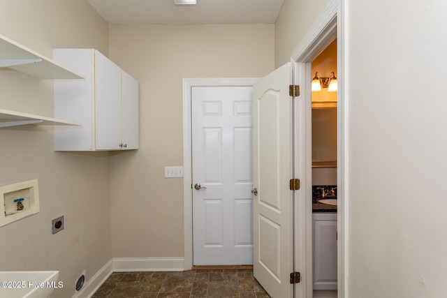 clothes washing area with hookup for an electric dryer, hookup for a washing machine, cabinet space, and baseboards