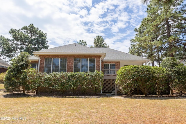 back of house featuring a yard, brick siding, and an attached garage