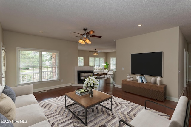 living area featuring ceiling fan, wood finished floors, recessed lighting, baseboards, and a textured ceiling